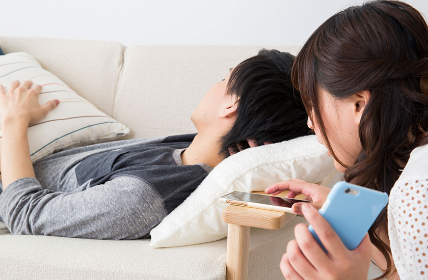 夫のスマートフォンを覗き見する女性